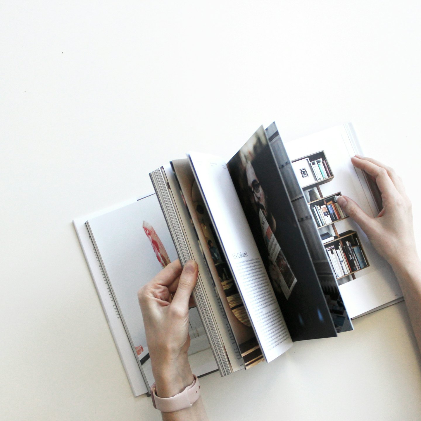 أيدٍ تمسك كتابًا مفتوحًا به نصوص وصور.